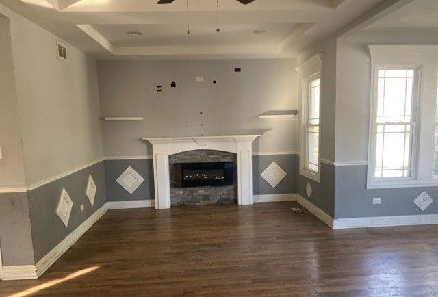 unfurnished living room featuring a wealth of natural light, dark wood-type flooring, and a tray ceiling