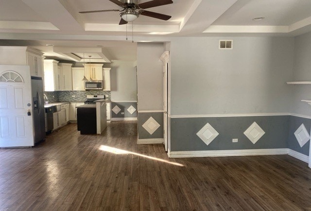 kitchen with dark hardwood / wood-style flooring, white cabinetry, appliances with stainless steel finishes, and a raised ceiling