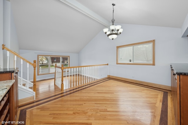 additional living space with vaulted ceiling with beams, an inviting chandelier, and light wood-type flooring