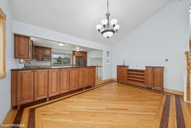 kitchen featuring kitchen peninsula, stainless steel appliances, a chandelier, and light hardwood / wood-style floors