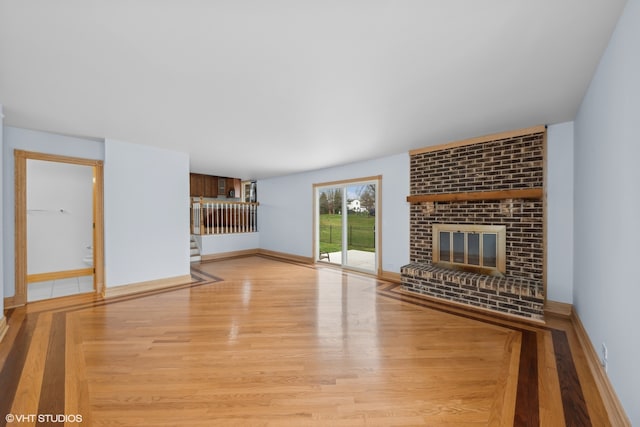 unfurnished living room with a brick fireplace and light hardwood / wood-style flooring