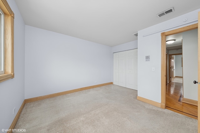 unfurnished bedroom with light carpet and a closet