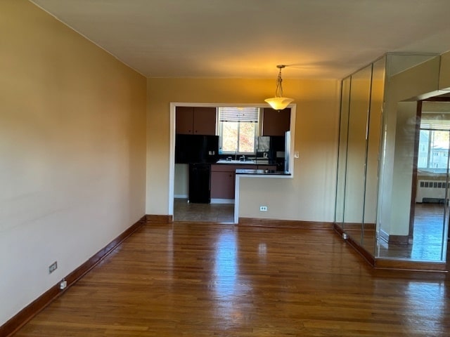 kitchen featuring dark brown cabinets, radiator heating unit, and dark hardwood / wood-style flooring