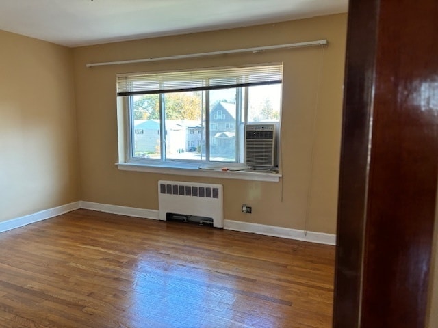 empty room featuring hardwood / wood-style floors, radiator, and cooling unit