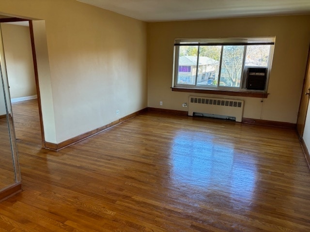 unfurnished room featuring hardwood / wood-style flooring, cooling unit, and radiator heating unit