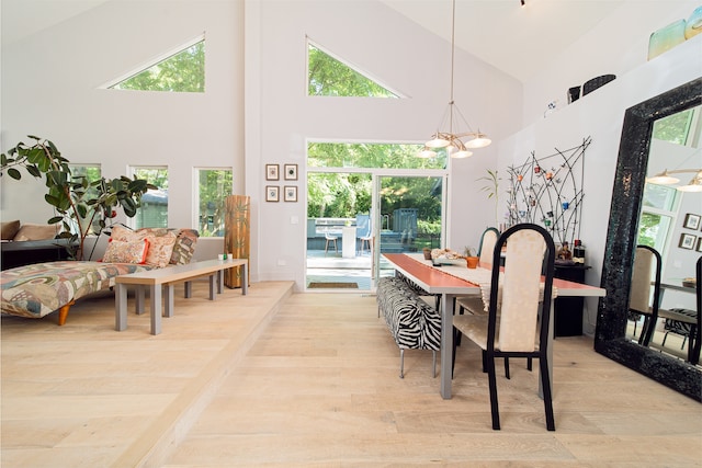 dining area featuring high vaulted ceiling, a chandelier, and light hardwood / wood-style floors