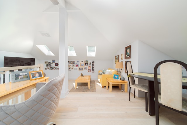 interior space featuring light hardwood / wood-style floors and vaulted ceiling with skylight