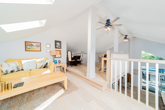 living room with hardwood / wood-style floors, ceiling fan, and lofted ceiling with skylight