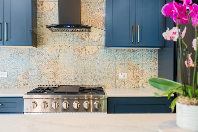 kitchen with tasteful backsplash, blue cabinets, wall chimney exhaust hood, and stainless steel appliances