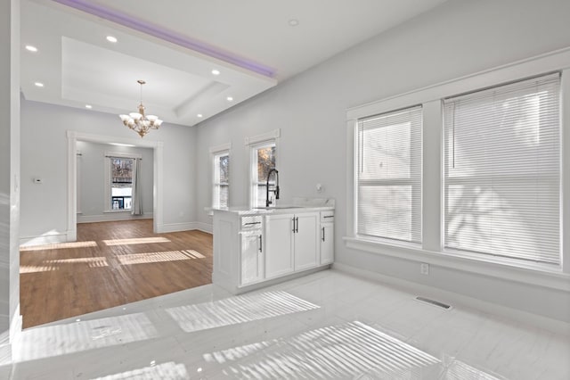 interior space featuring light wood-type flooring, sink, a tray ceiling, and a chandelier