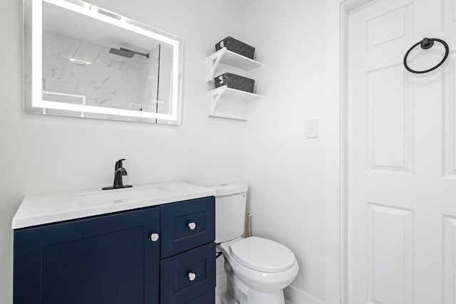 bathroom with a tile shower, vanity, and toilet