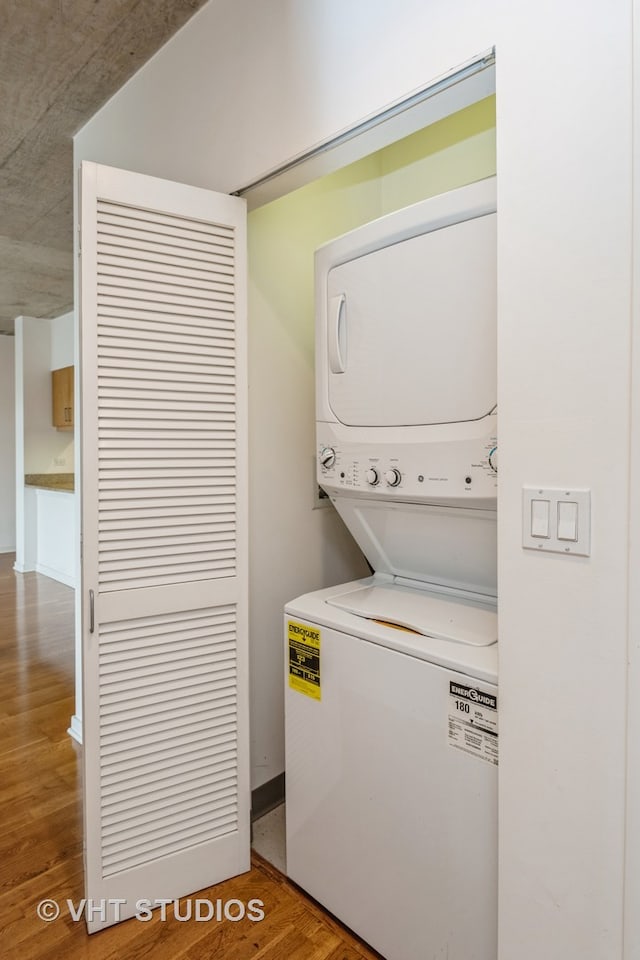 washroom featuring hardwood / wood-style floors and stacked washer and clothes dryer