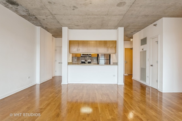 unfurnished living room with light wood-type flooring and sink