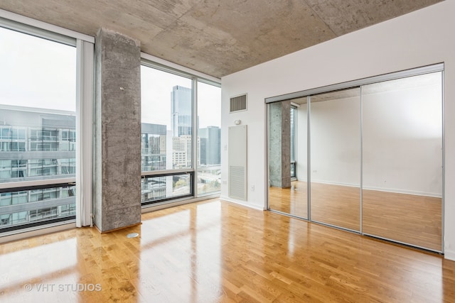 unfurnished bedroom featuring floor to ceiling windows, a closet, and light hardwood / wood-style flooring