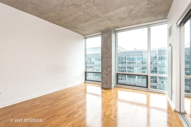 unfurnished room with hardwood / wood-style flooring, floor to ceiling windows, and a wealth of natural light