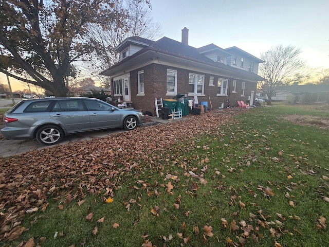 property exterior at dusk featuring a lawn