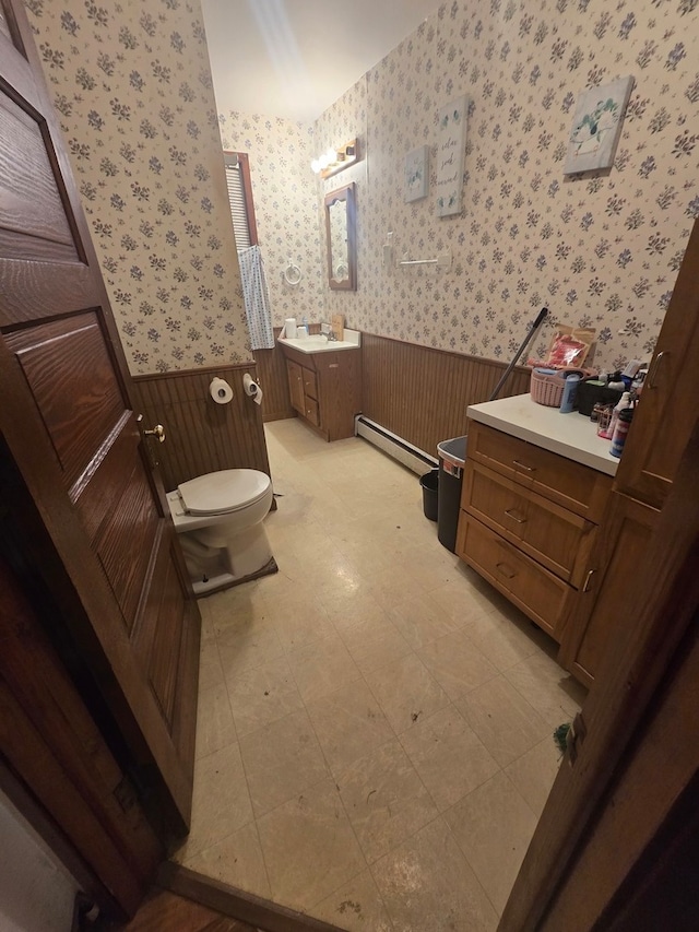 bathroom featuring a baseboard heating unit, vanity, toilet, and wood walls