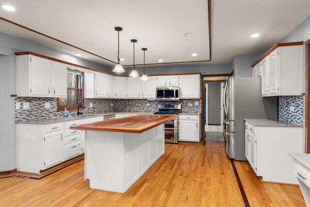 kitchen with light wood-type flooring, white cabinetry, stainless steel dishwasher, and a kitchen island