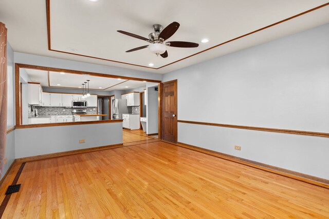 unfurnished living room featuring a brick fireplace, light hardwood / wood-style flooring, and ceiling fan