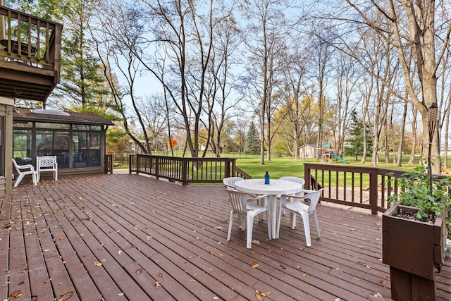 deck with a playground, a yard, and a sunroom