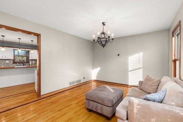 living room featuring light hardwood / wood-style flooring, sink, and a chandelier