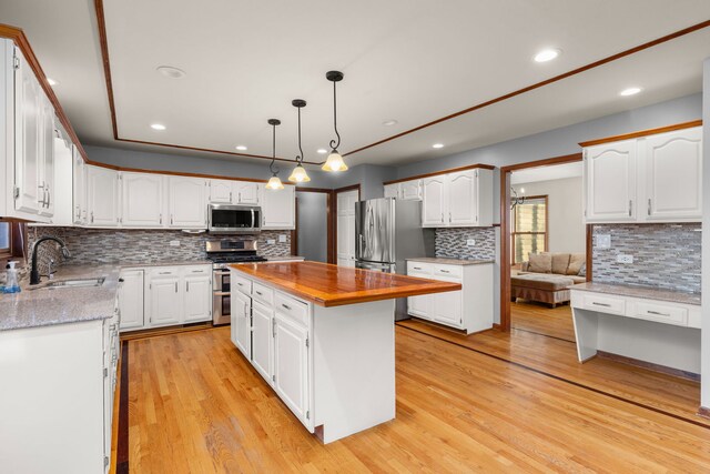 kitchen featuring a center island, decorative backsplash, appliances with stainless steel finishes, light hardwood / wood-style floors, and white cabinetry