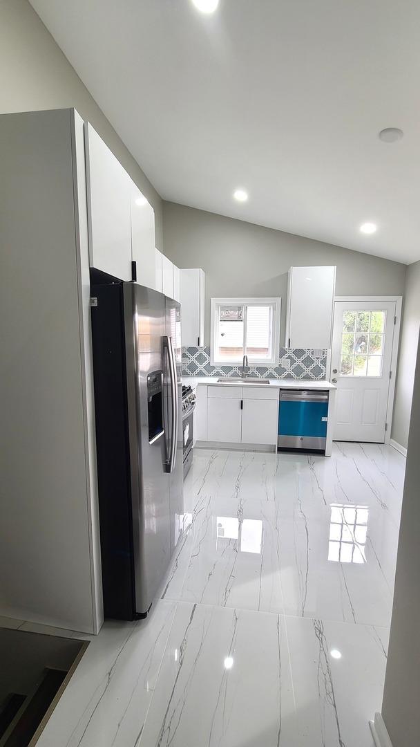 kitchen with white cabinets, lofted ceiling, stainless steel appliances, and tasteful backsplash