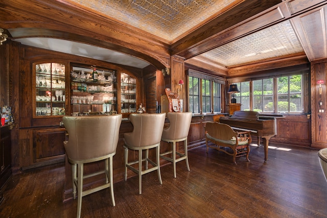 bar with wood walls, crown molding, and dark hardwood / wood-style flooring