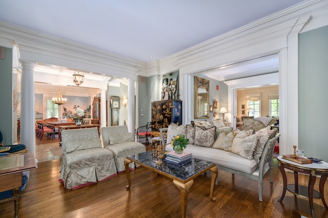 living room with a chandelier, hardwood / wood-style flooring, ornate columns, and crown molding