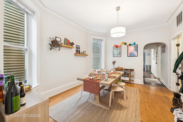 dining space featuring light wood-type flooring and crown molding