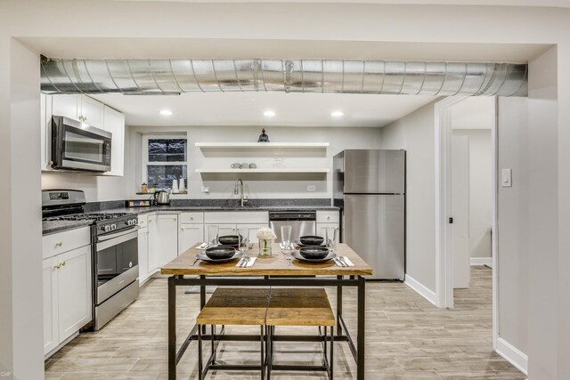 kitchen featuring light wood-type flooring, stainless steel appliances, white cabinetry, and sink