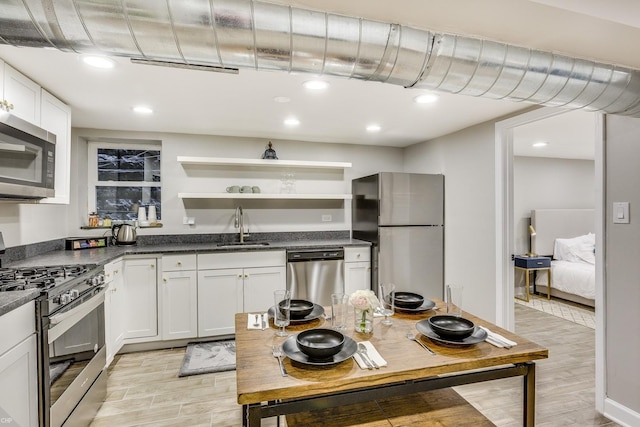 kitchen with white cabinets, sink, light wood-type flooring, and stainless steel appliances