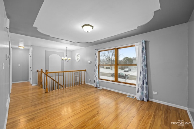 spare room featuring light hardwood / wood-style flooring and a notable chandelier