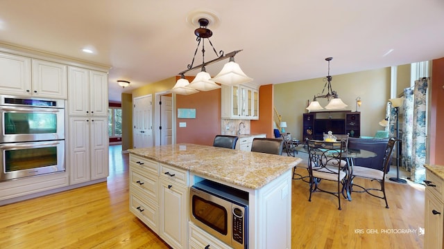 kitchen with pendant lighting, white cabinetry, a kitchen island, and appliances with stainless steel finishes