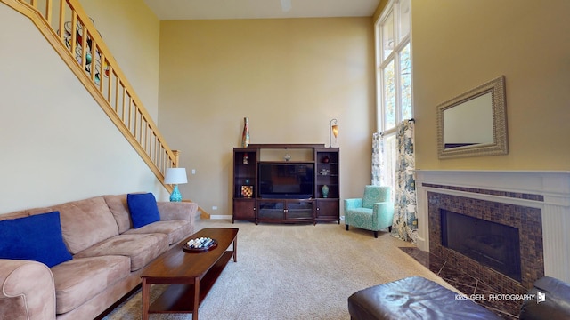 carpeted living room with a high ceiling and a tile fireplace