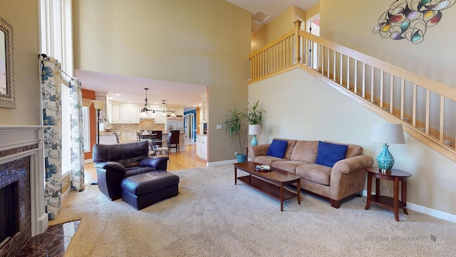 carpeted living room featuring a tile fireplace and a high ceiling