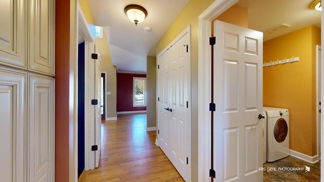 hall with washer / clothes dryer and light wood-type flooring