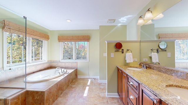 bathroom with tiled tub, vanity, and tile patterned flooring