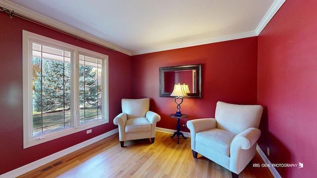 sitting room with crown molding and light hardwood / wood-style floors