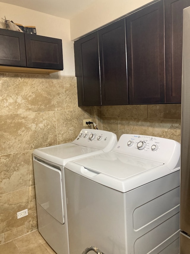 laundry room featuring independent washer and dryer, cabinets, and light tile patterned floors