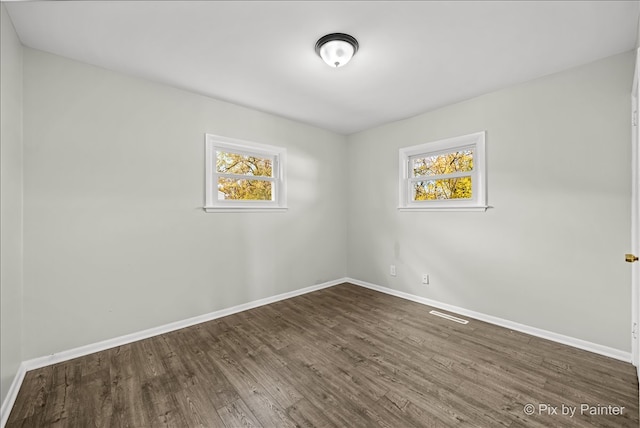 spare room with dark hardwood / wood-style flooring and plenty of natural light