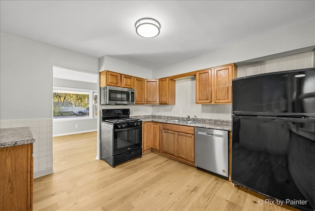 kitchen with black appliances, sink, and light hardwood / wood-style flooring