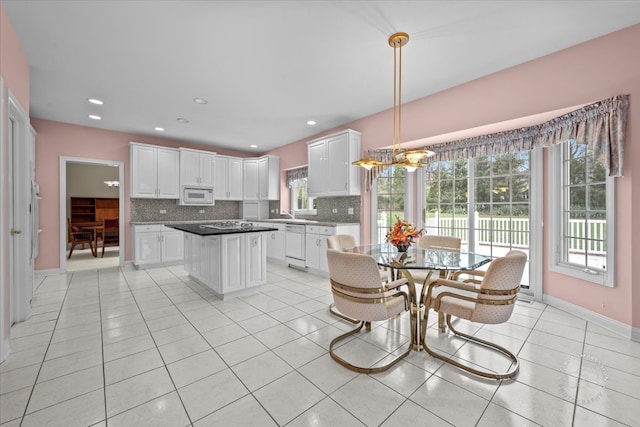 kitchen with white cabinets, backsplash, pendant lighting, white appliances, and light tile patterned floors