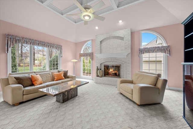 carpeted living room featuring a towering ceiling, a brick fireplace, coffered ceiling, ceiling fan, and beamed ceiling