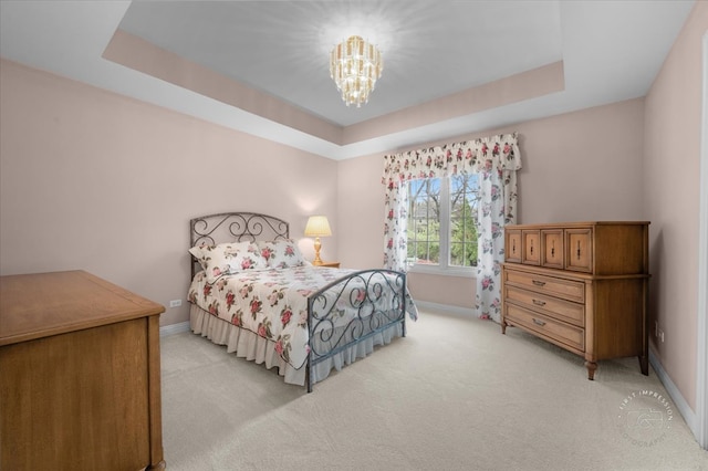 bedroom featuring a tray ceiling, an inviting chandelier, and light colored carpet