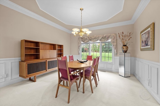 dining room with ornamental molding, light colored carpet, an inviting chandelier, and a tray ceiling