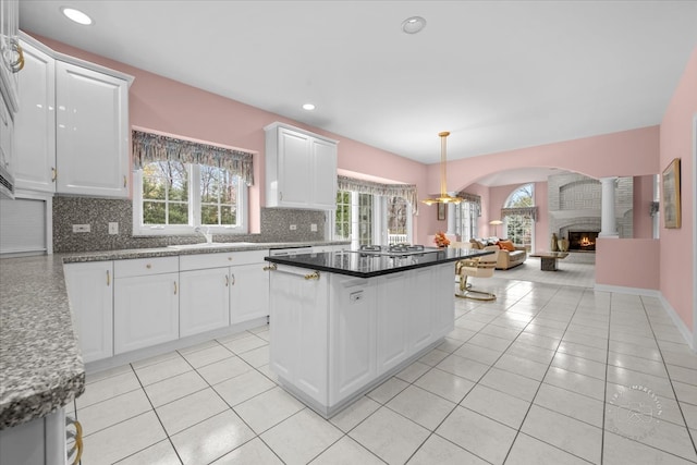 kitchen featuring decorative backsplash, a fireplace, white cabinets, and a kitchen island