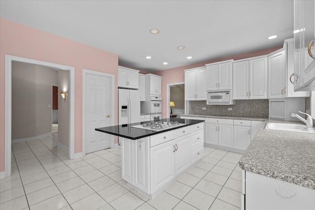 kitchen featuring a center island, sink, white appliances, decorative backsplash, and white cabinets