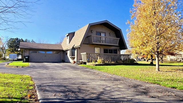 front facade featuring a front yard, a balcony, and a garage