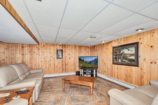 living room featuring a drop ceiling, baseboard heating, and wood walls